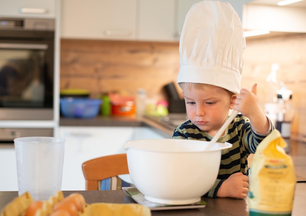 コック帽をかぶった子供が料理をしています