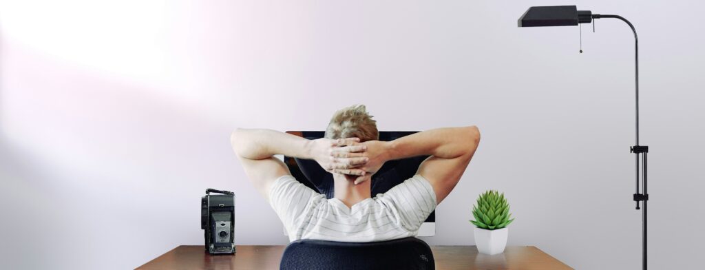 椅子に座りながら考えている男性の後ろ姿