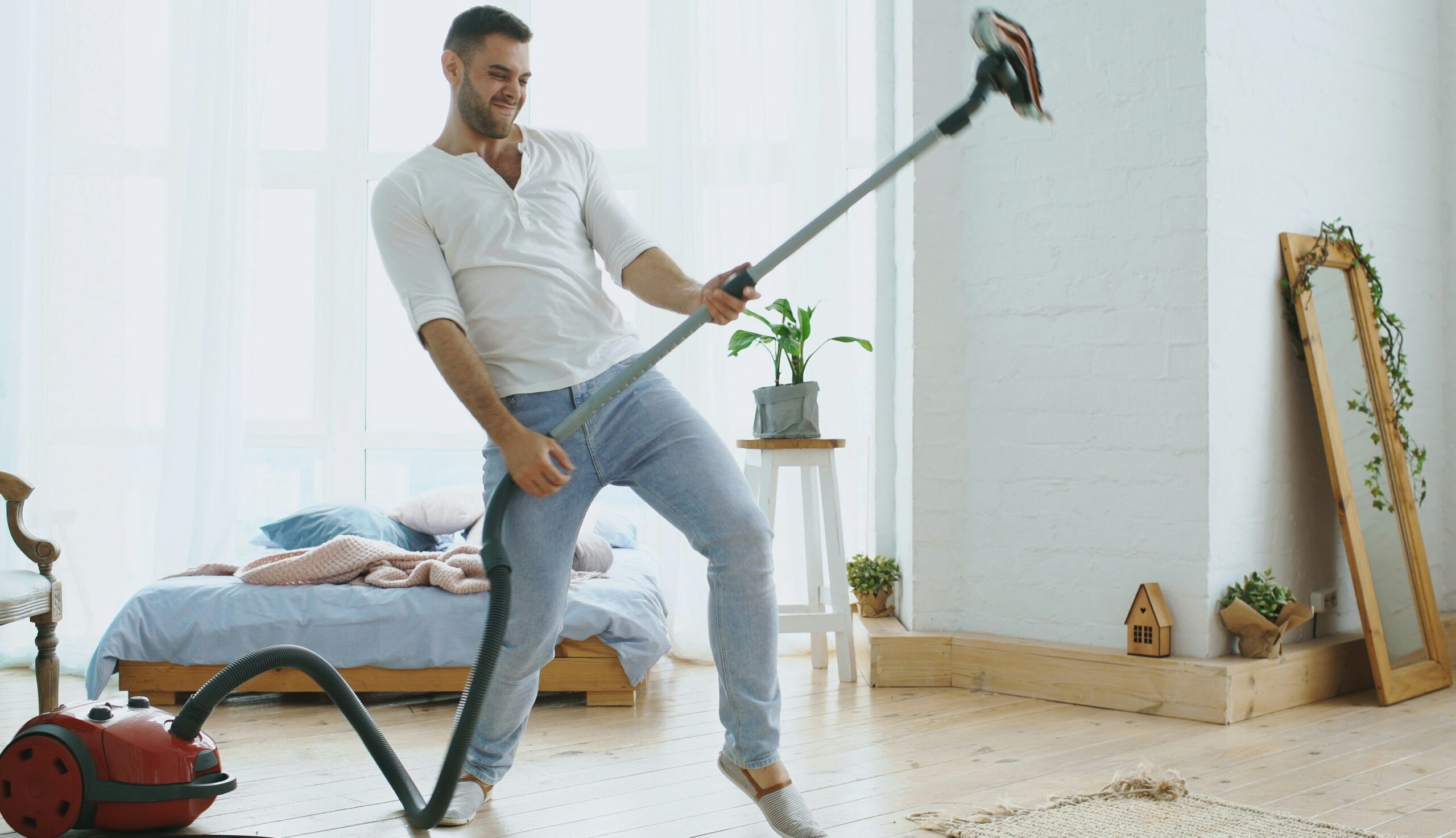 男性が掃除機をギターにして遊んでます